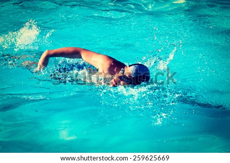 Vintage retro effect filtered hipster style image of athletic Man swimming in the pool