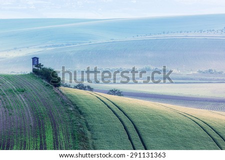 Rural Europe background - Moravian rolling landscape with hunting tower shack in early morning on sunrise. Moravia, Czech Republic