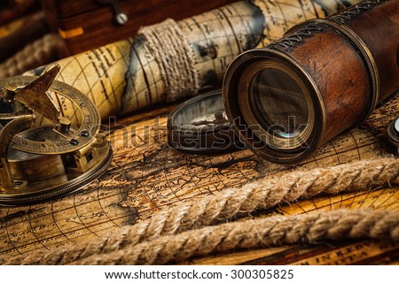 Travel geography navigation concept background - old vintage retro compass with sundial, spyglass and rope on ancient world map