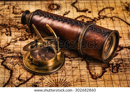 Travel geography navigation concept background - old vintage retro compass with sundial and spyglass on ancient world map