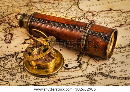 Travel geography navigation concept background - old vintage retro compass with sundial and spyglass on ancient world map