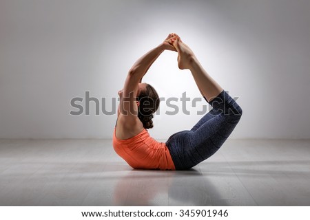Sporty fit woman practices yoga asana Dhanurasana - bow pose