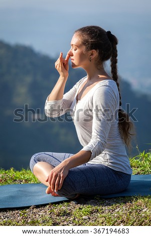 Yoga position meditation healthy life exercise concept - Woman practices pranayama yoga breath control in lotus pose padmasana outdoors in Himalayas in the morning on sunrise. Himachal Pradesh, India