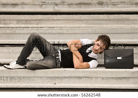 Young tired man sleeping with head resting on a briefcase