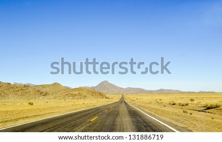 Long, straight road with horizon blue sky and mountains. Grand Canyon. Arizona. USA