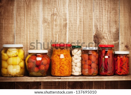 Preserved Autumn Vegetables On Shelf Near A Brown Wooden Wall