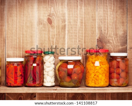 Preserved  autumn vegetables on shelf near a brown wooden wall