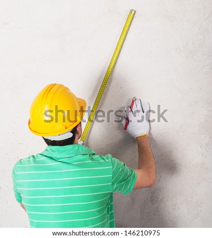 worker measuring plaster wall