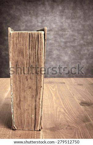 Vintage book on brown table made of wooden planks near concrete wall.