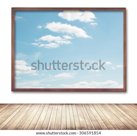 Wooden frame with cloud and sky picture hanging on wall near sidewalk