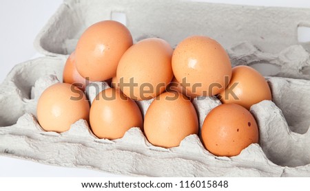 A dozen eggs piled in the carton.