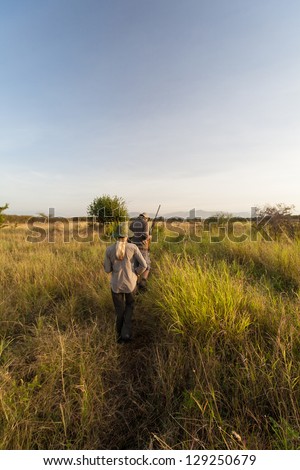 A male and female ranger make their way through the bush in Tanzania\'s wilderness. Manyara Ranch Conservancy, Tanzania