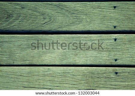 Detail shot of three aged wood boards with nails holding them down. Grain and scratches in the surface can be seen. Charleston, South Carolina.