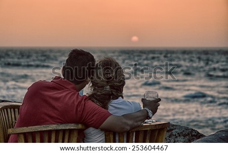 Cartagena, Colombia - February 23, 2014 - A couple shares a romantice moment as they drink wine and watch the sun set over the Caribbean ocean from the old walls of Catagena.