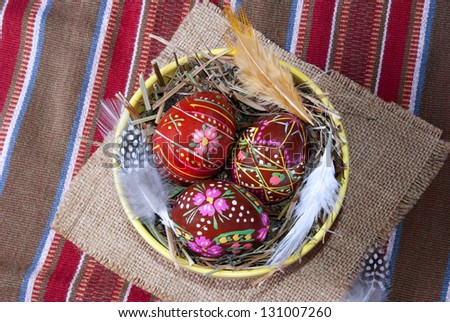 Three brown painted Easter eggs on straw in a plate, a kind with top