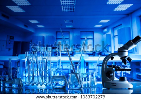 Science Concept. Laboratory Research and Development. Scientific glassware for chemical experiment. Microscope, laboratory beakers, test tubes, pipettes. Lab interior background.