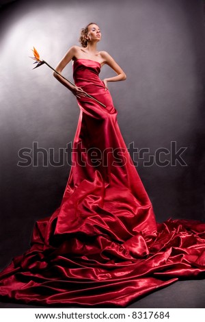 stock photo The beautiful girl in a long red dress holds an exotic flower