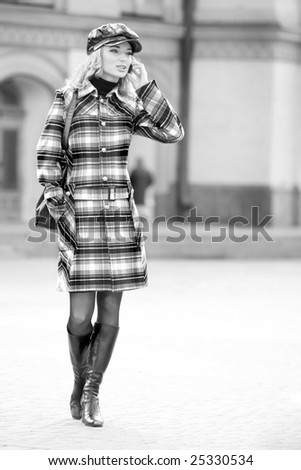 Beautiful young blond in a coat talks on the phone. Photography for fashion brand Catalog clothes