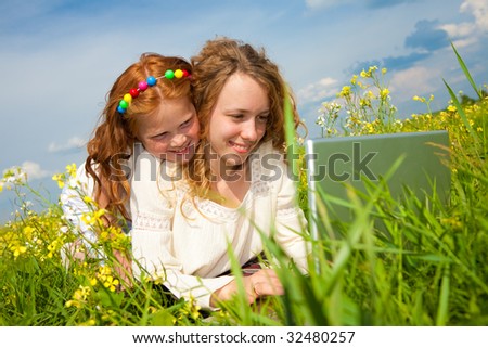 mother and daughter lay on a grass with a notebook