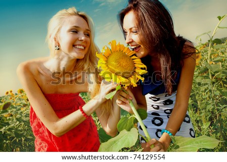 two girlfriends having fun in field of sunflowers