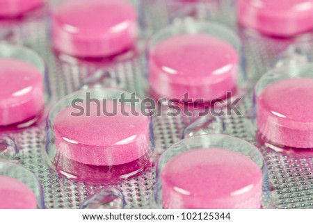 Bright pink pills packed in transparent plastic package
