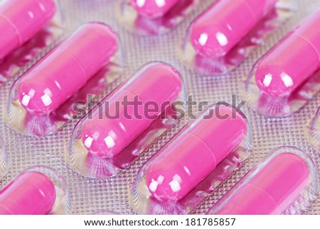 Macro bright pink pills packed in transparent plastic package