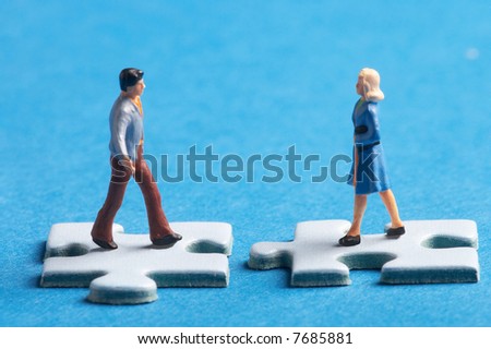 two plastic figures standing on two puzzle pieces