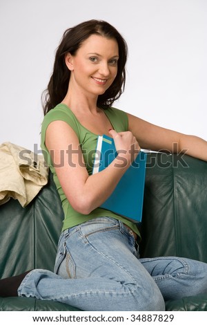 young woman sitting on a green couch with book
