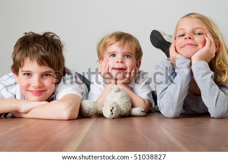 Two boys and one girl are lying on the floor