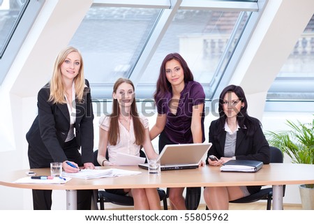 four business women with laptop in front of the window