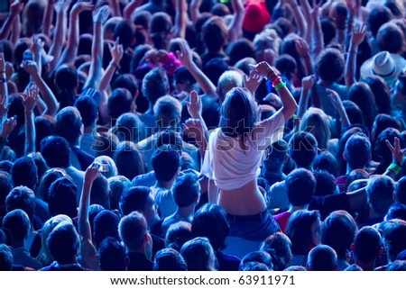 girl cheering with crowd and sitting upon the shoulders of her friend