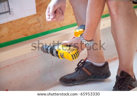 fixing a wooden slat with a yellow drilling machine