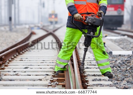 the railroad worker fixes a screw on the rails