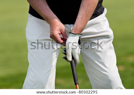 man golfs while wearing a blue polo and white trousers
