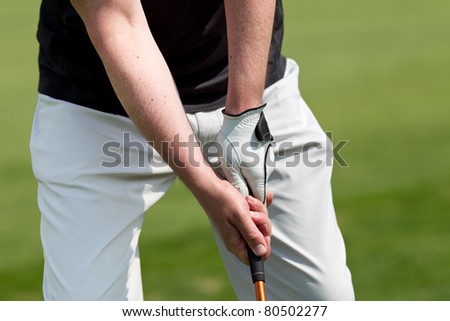 man playing golf while wearing a blue polo and white trousers