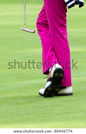 golfer wearing pink slacks and white shoes