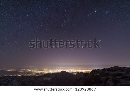 A view from midway up Mount Lemmon, looking down into Tucson, Arizona.  Orion, Jupiter, and the Pleiades float above the city lights.
