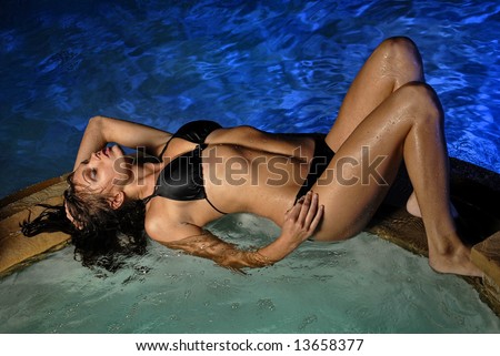 Beautiful young Sexy woman lying down on edge of Jacuzzi in pool