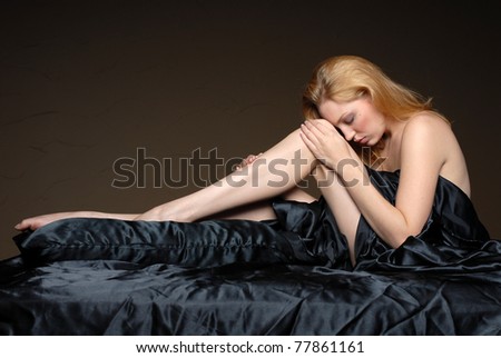 Beautiful woman relaxing on black satin sheets