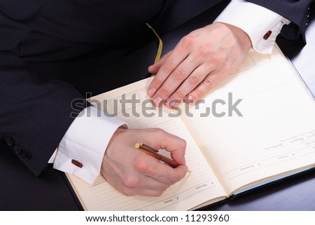 Hand of businessman taking notes at board meeting