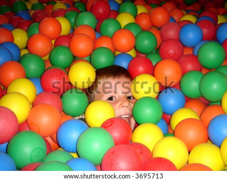 boy playing in bouncy castle with lots of colored plastic balls