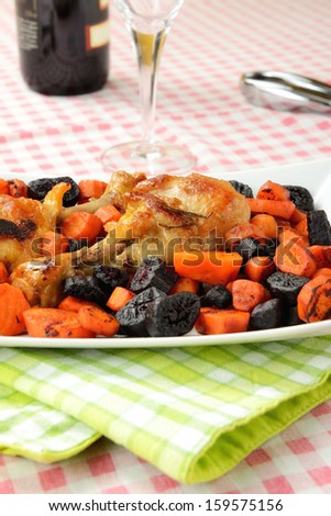 Plate of chicken thighs with black and orange carrots