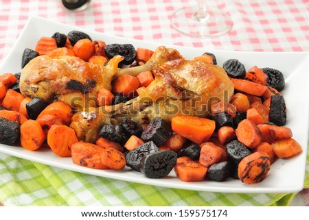 Plate of chicken thighs with black and orange carrots