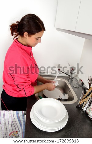 girl washes dishes by hand in the sink