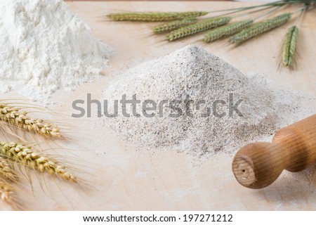Wooden board with different types of flour and a rolling pin