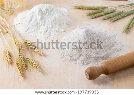 Wooden board with different types of flour and a rolling pin
