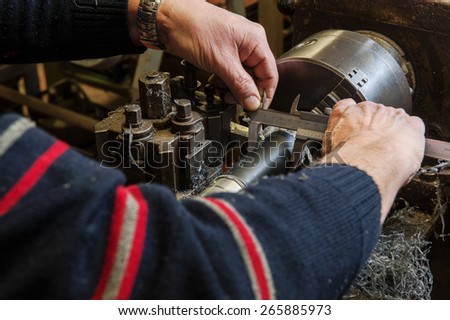 Craftsman mechanical measuring a piece on the lathe