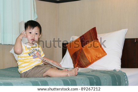Little boy play phone on bed room