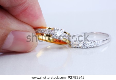 Hand pick golden ring with diamond and contemporary diamond ring, isolated on white background.