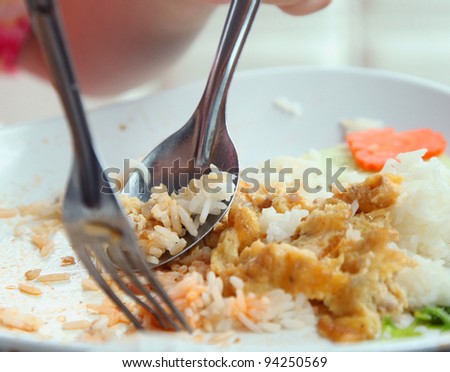 Hand holding spoon and fork on eating rice with omelet.